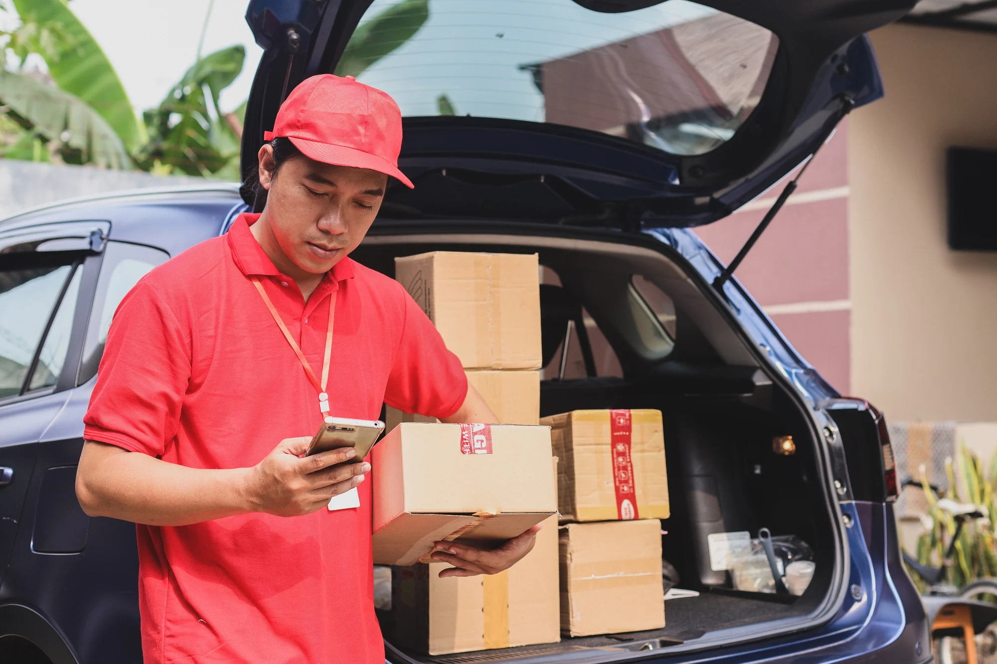 Delivery Man With Cardboard Box Checking List On Mobile Phone